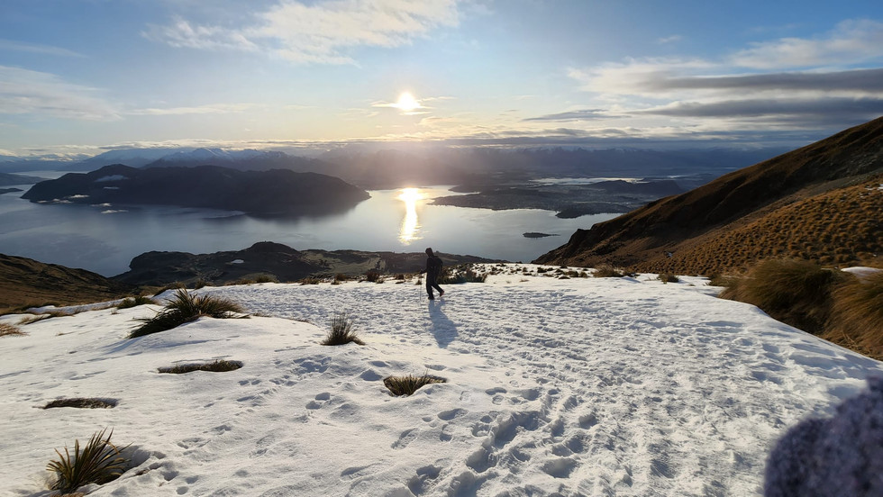 Sunrise over Lake Wanaka and a person walking in the snow