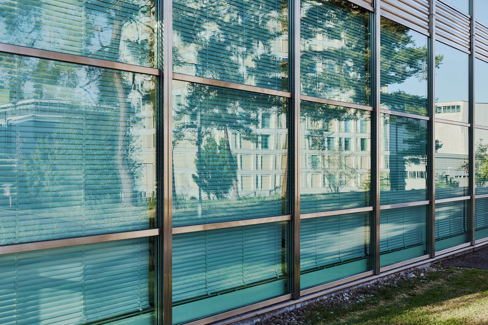 Glasfassade mit Spiegelungen und geometrischem Fassadenraster