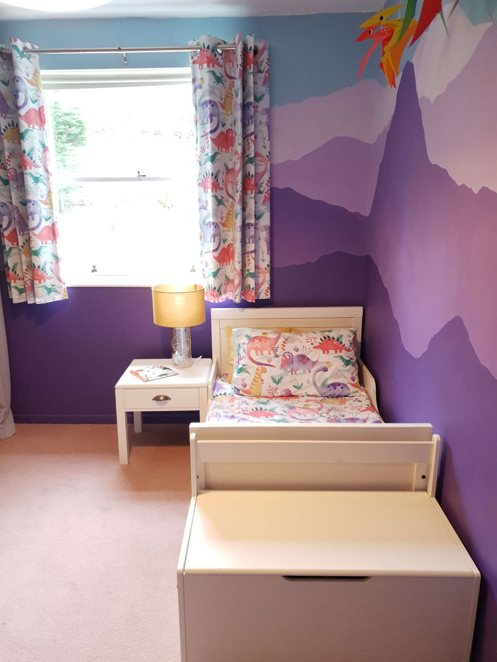 A bedroom with dinosaur bedding on a single bed and purple walls NEW