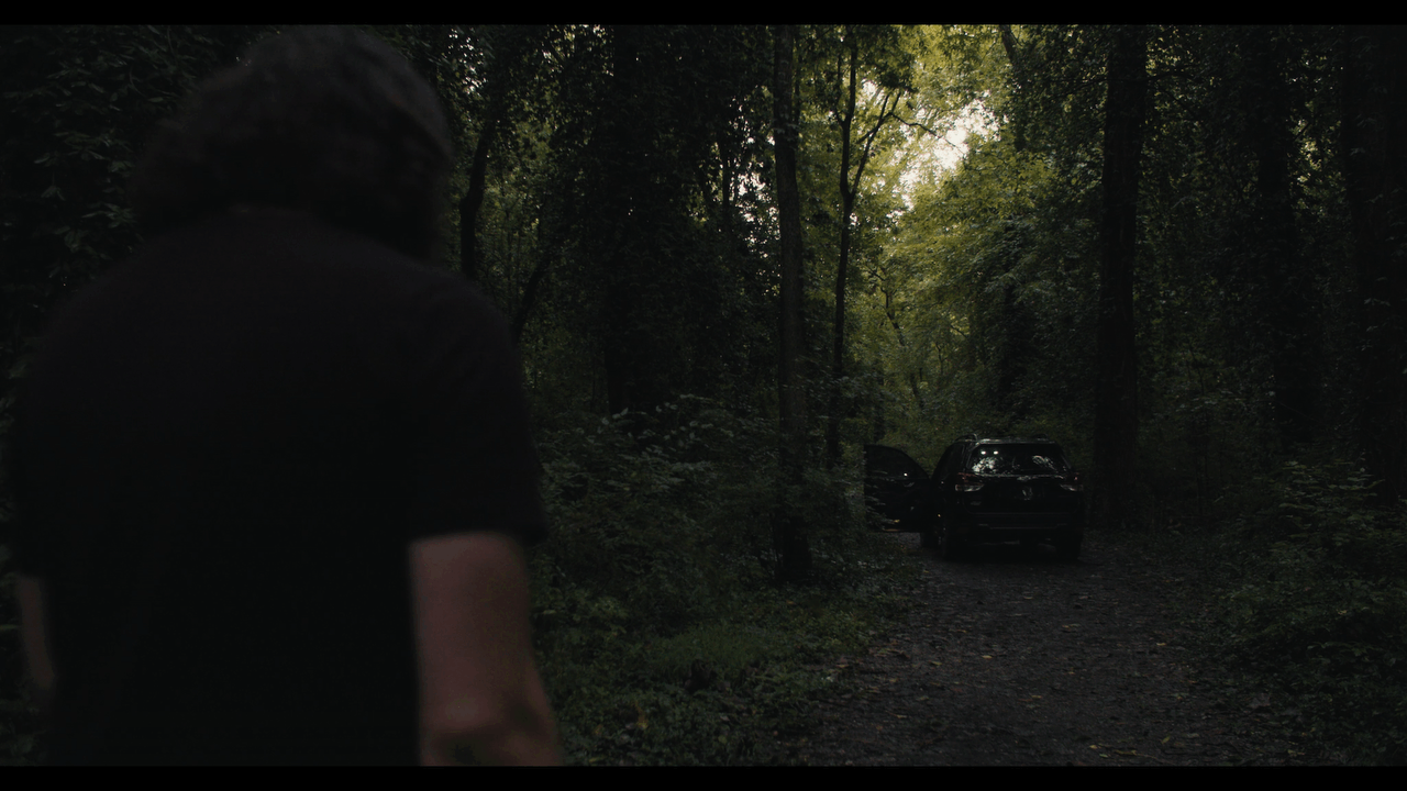 directed by adam settle credit over professional videography of a man approaching a car in the woods that feels like a horror film