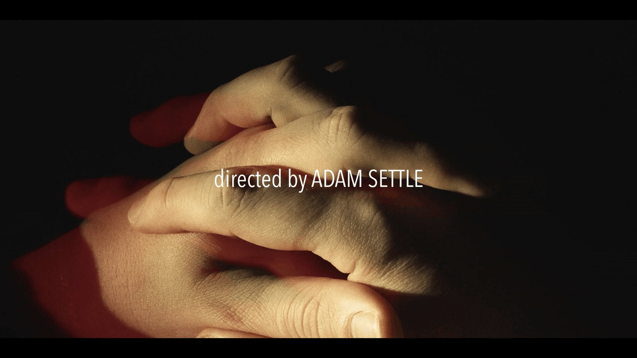 directed by adam settle credit over two hands holding under warm cinematic professional lighting