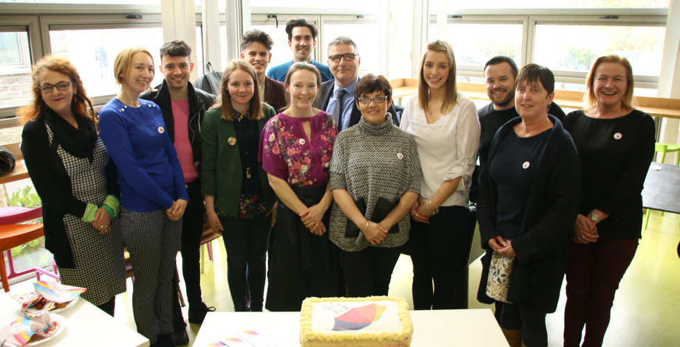 Group smiling for photo with cake