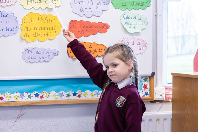 Girl points to classroom question board to learn Irish words (Online Only do NOT Print )