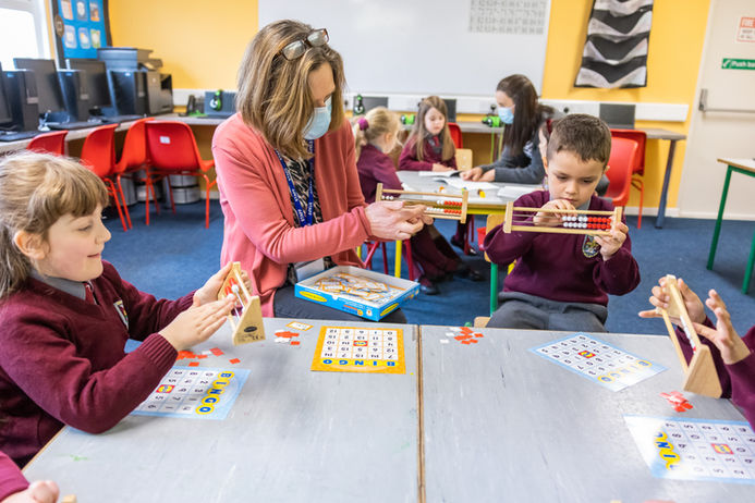 Teacher assisting students with math tools in classroom (Online Only do NOT Print )