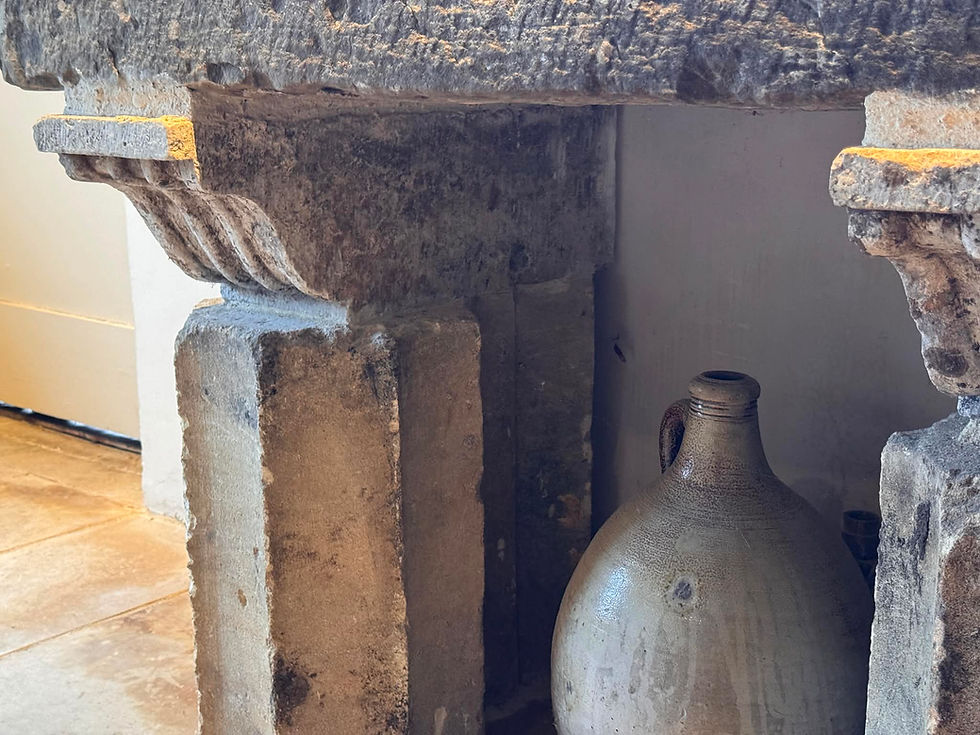 A view of the stonework supporting the sink. Traces of carvings and original shapes are partially visible. Between the two stone supports is a very large earthenware vessel.