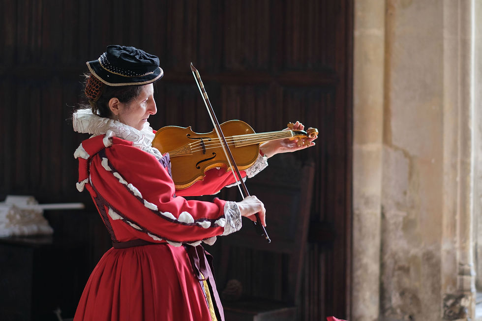 A Tudor lady in a red gown with slashed sleeves, embroidered cuffs, a ruff, and a black velvet hat and beaded caul tunes a violin, with dark panelling behind her.