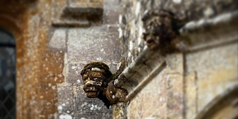 A close up of a grotesque on the top of the oriel window, turning to look towards the camera