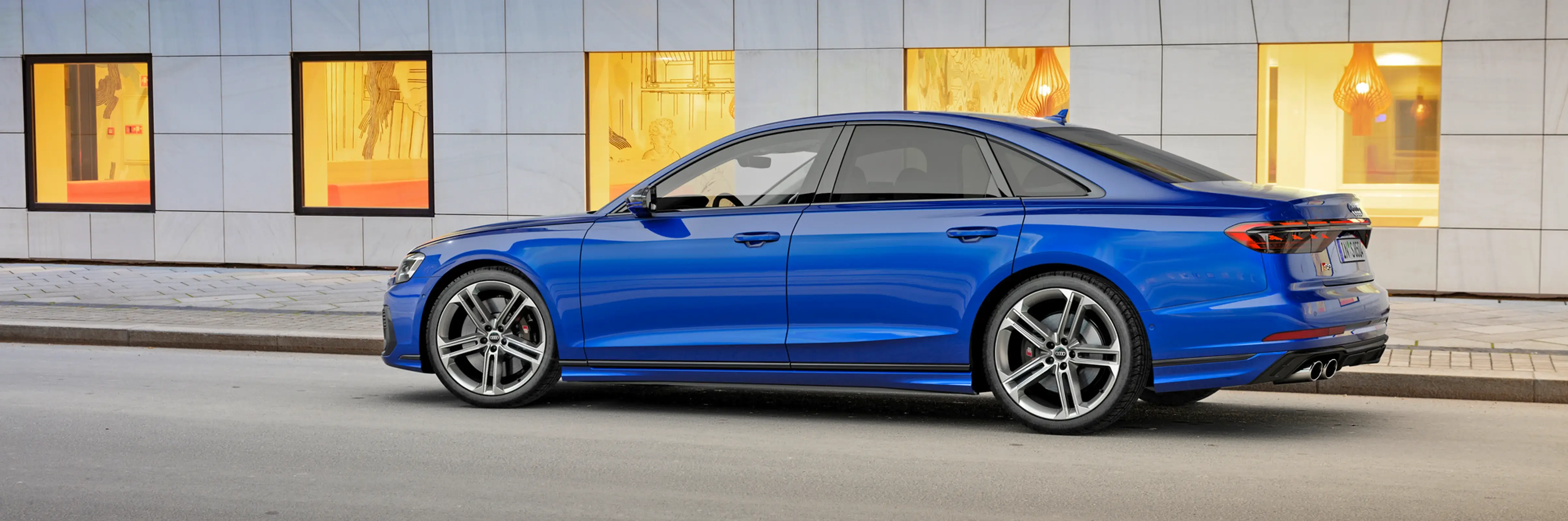 Audi S8 blauw zijkant voor muur met vier lijsten.jpg.webp