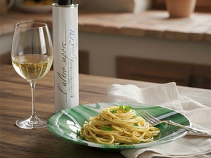 Spaghetti al limone with olive oil in a green Murano Glass Bowl with a glass of white wine and Italian organic olive sit on a rustic wood table