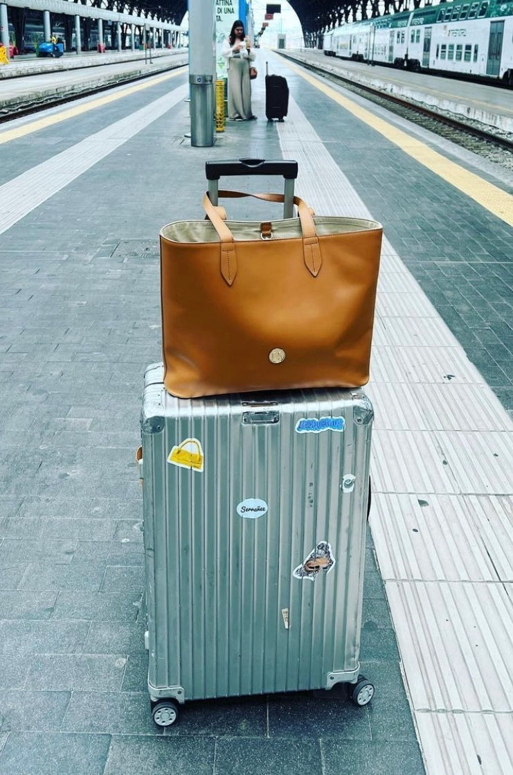 Italian leather camel colored travel bag with luggage in italian train station