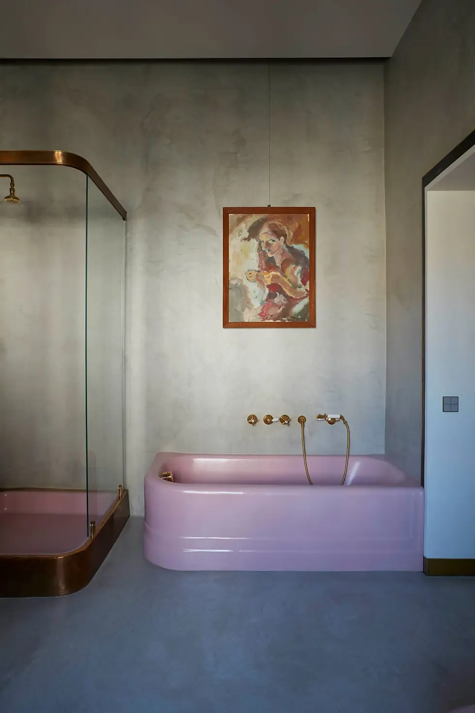 pink bathtub and shower with artwork above bathtub