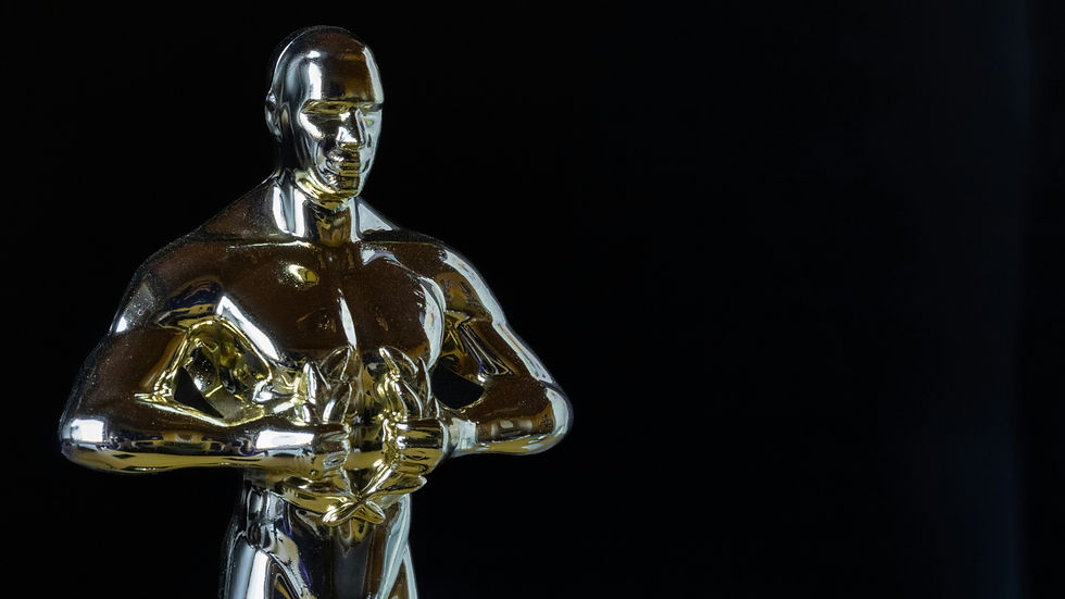 Golden trophy statue against a black background, reflecting light. The figure has muscular details and no visible text. Classic and elegant.