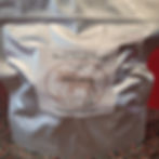 "Silver package labeled 'Chicken Alfredo' by Moose Island Foods. Includes details like its origin ('Made in Wells, BC, Canada') and a handwritten price tag of '$26.25.' The package sits on a patterned surface.