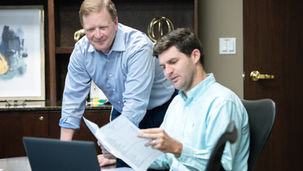 Two bankers working together looking at documents and a computer
