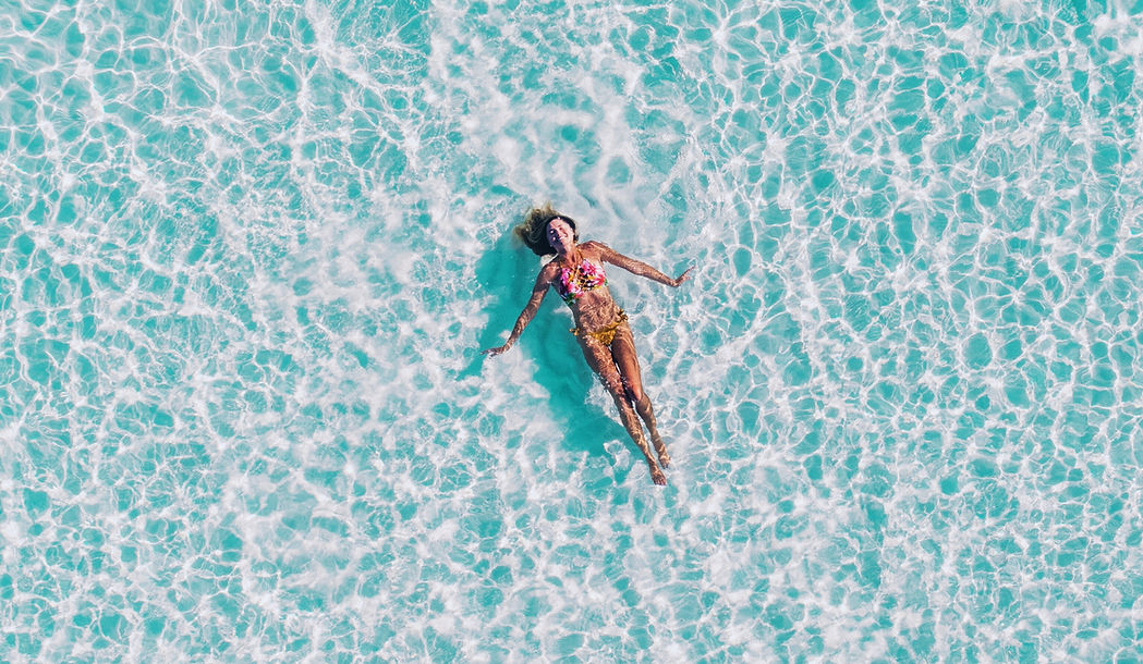 Girl floating in the sea in turquoise water.