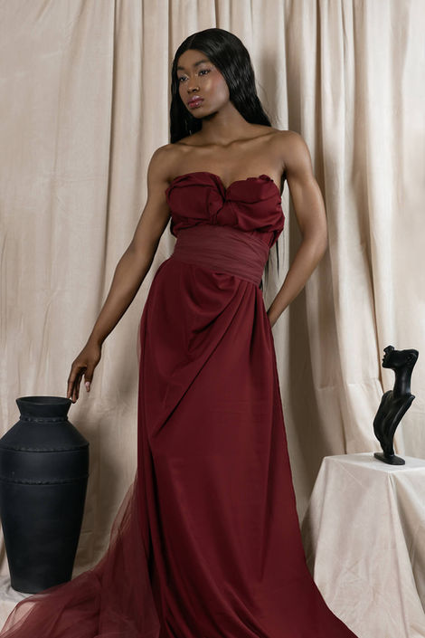 Black female model wearing red dress looking off to the side in a portrait photo studio