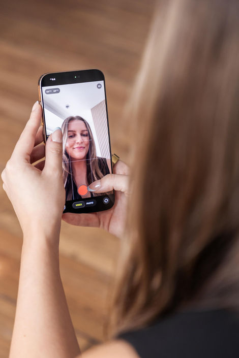 A close-up, over-the-shoulder shot of a woman recording a selfie video on her iPhone. This creative branding photography highlights the content creation process for influencers and digital entrepreneurs in the GTA.