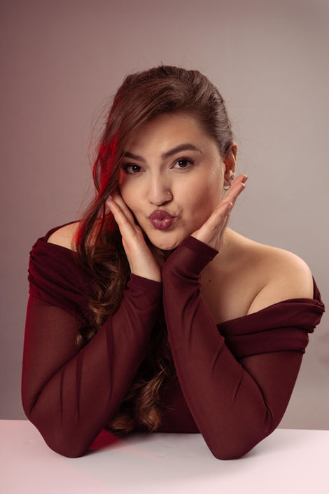 High-resolution beauty headshot of a woman in a maroon top. Soft-focus studio photography emphasizing professional makeup and hair styling for a salon branding session.