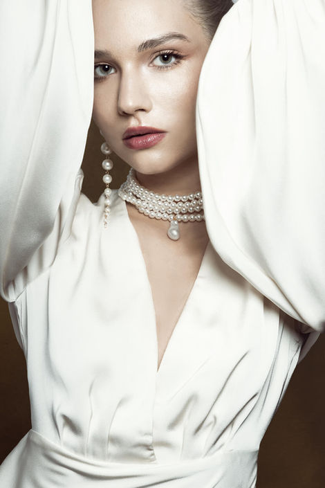 Model with raised hands in white dress in a glamour fashion portrait