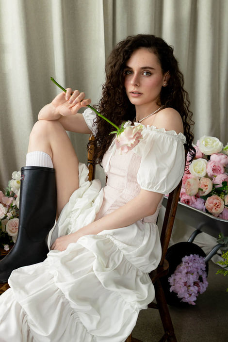 Intimate beauty and fashion portrait of a model holding a pink rose, emphasizing soft textures and professional studio lighting