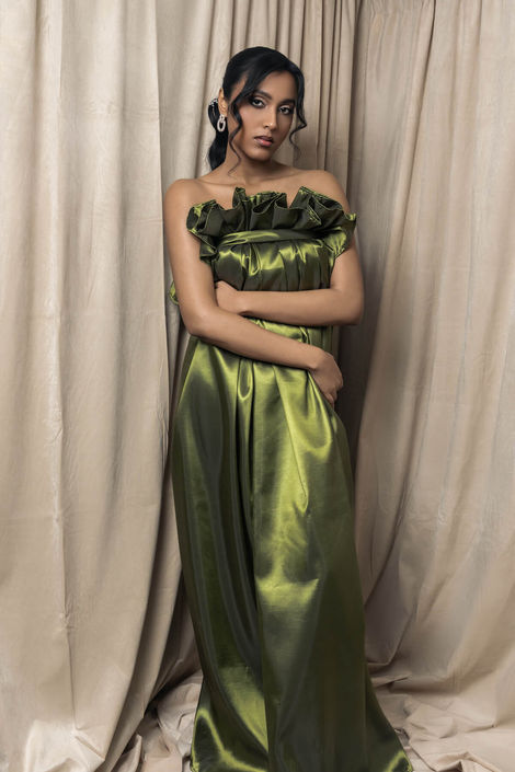 Artistic studio portrait of a woman in a draped olive green satin dress, highlighting sophisticated poses and professional lighting for a luxury brand.