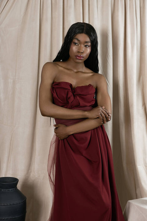 Portrait of a black female model wearing a red dress hugging herself