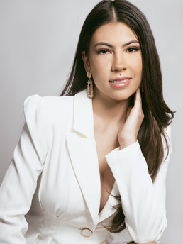 female in white power suit with hand on face posing for branding photography