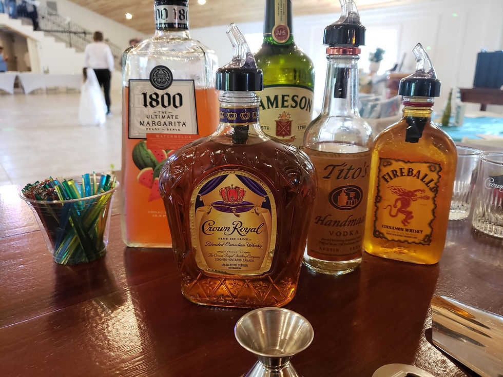 Liquor bottles and bartending tools arranged on an event bar top
