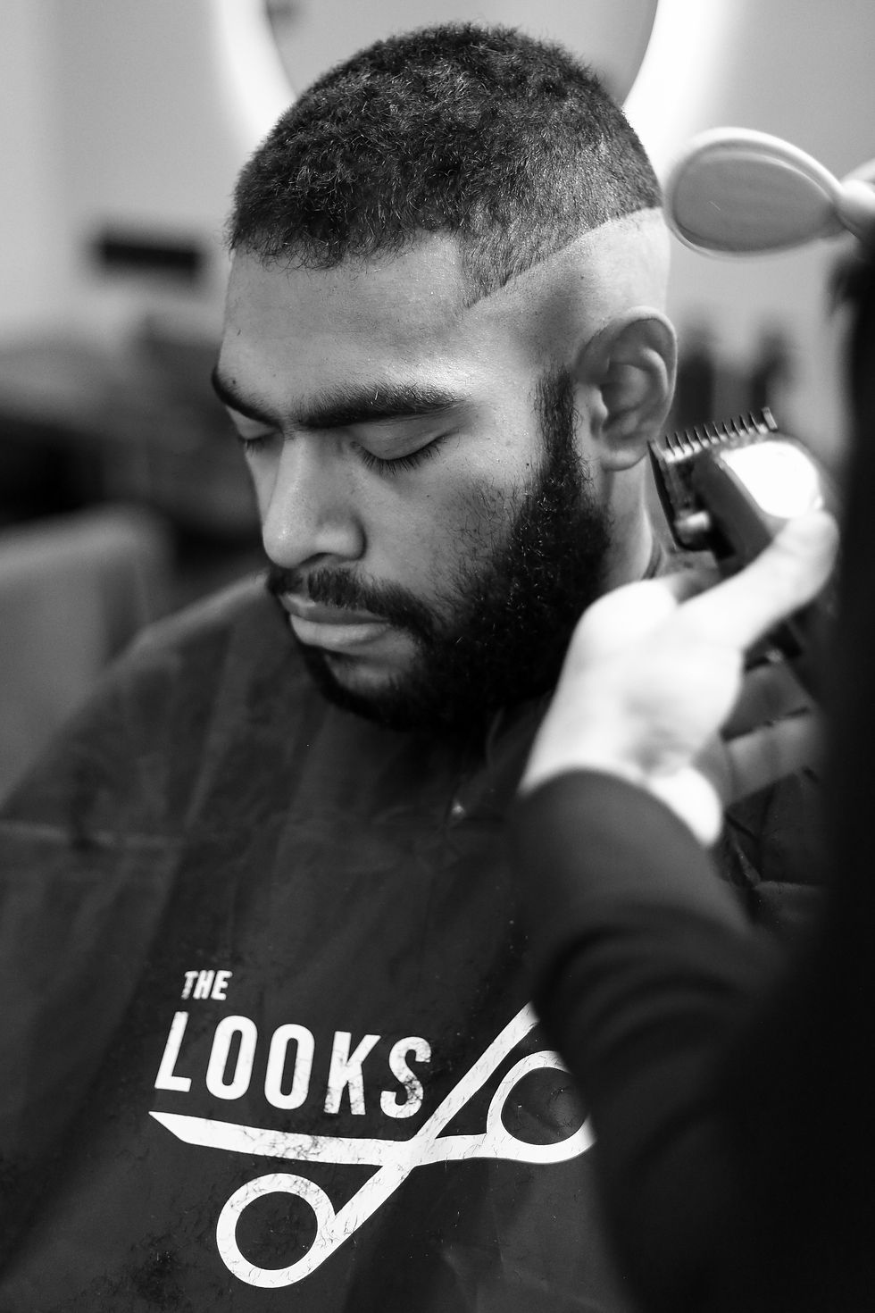 Barber provádí úpravu vlasů muži s krátkým účesem v salonu The Looks.