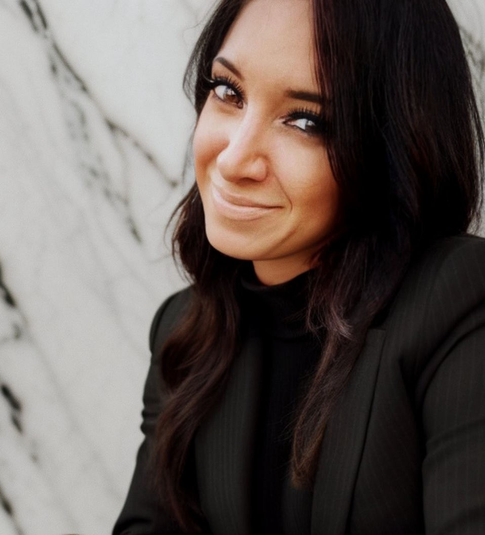 A professional artist and home stylist wearing a black blazer with a marble black and white background