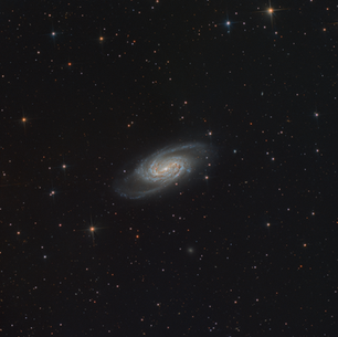 Imagen astronómica de la galaxia espiral barrada NGC 2903 en la constelación de Leo, mostrando su núcleo brillante y brazos espirales rodeados por estrellas del fondo del espacio.