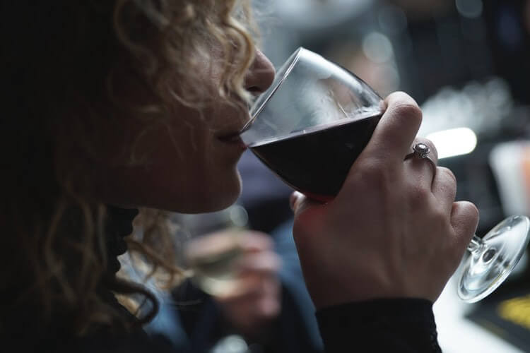 Blonde Frau nippt an Glas Rotwein