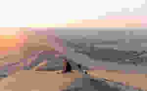 Zwei Personen sitzen auf Sanddüne in der Ica Wüste, Peru