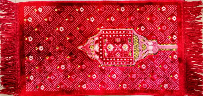Maroon red prayer rug with fringed edges on the short sides The velvety surface features r
