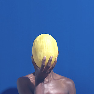 Black woman's hand holding a melon in front of her face