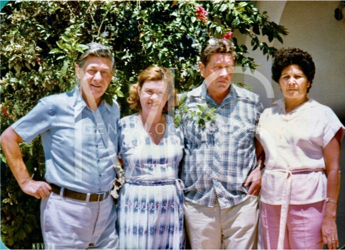 Four people stand side by side in front of leafy greenery. Two men and two women, wearing casual clothes, appear calm and relaxed.