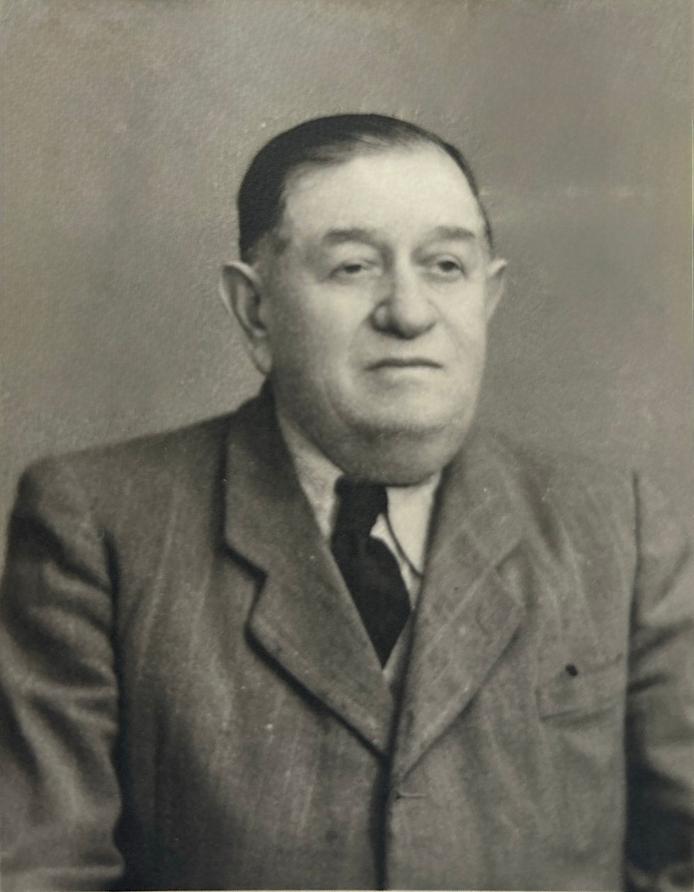 Black-and-white portrait of an older man in a suit and tie, neutral expression, plain background, evoking a formal, historical mood.