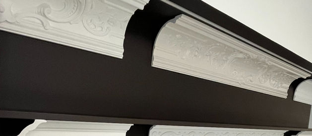 ベルギーのモールディングメーカーのショールームにて。黒い壁面に美しく整列した、多様なデザインの白いモールディングのライン。