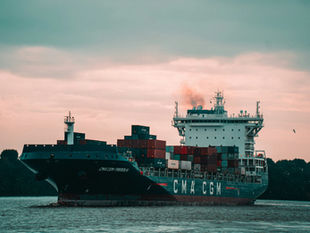 A cargo ship arriving in Hamburg harbour. Photo by Mika Baumeister on Unsplash.