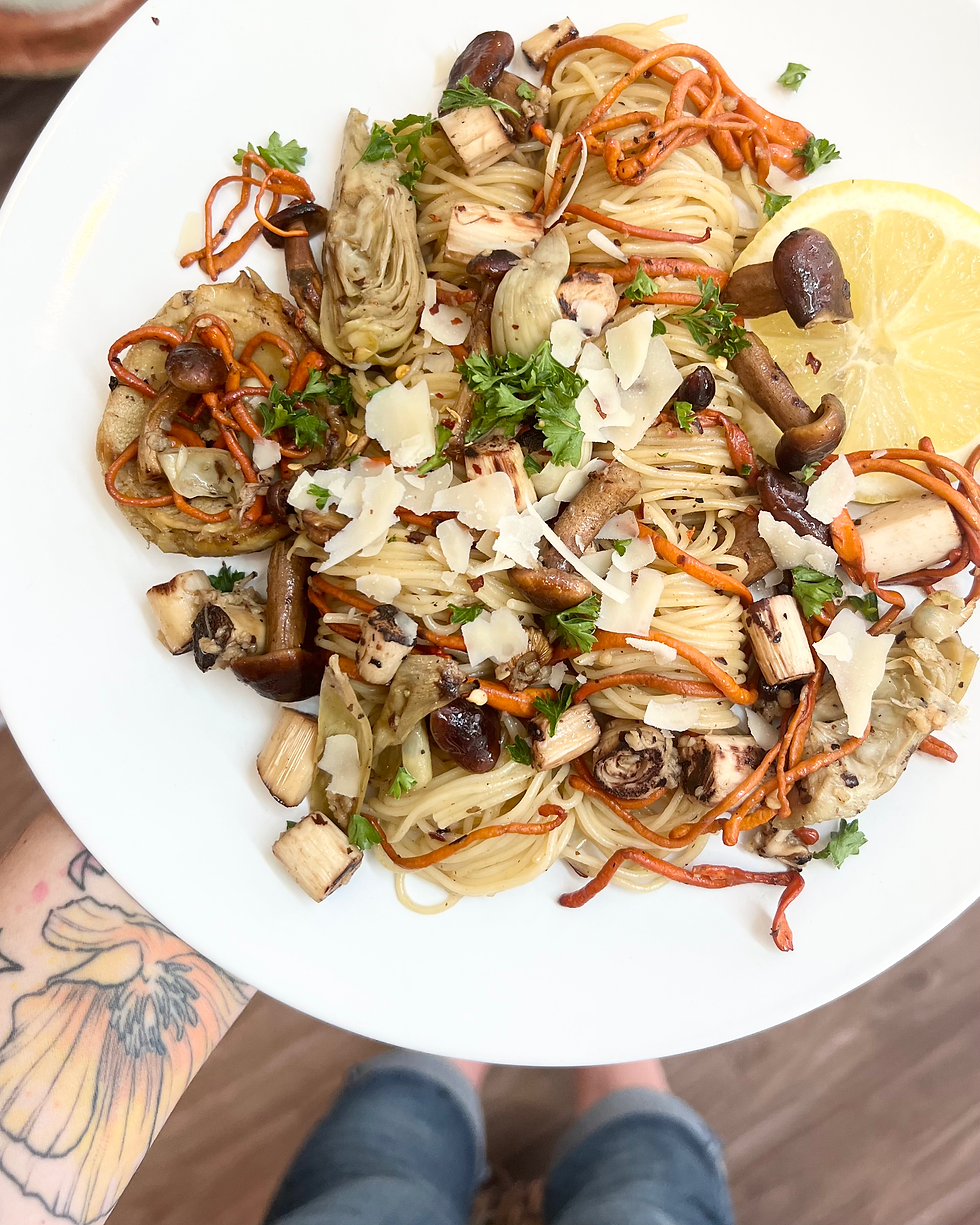 A bowl of plant-based pasta with mushrooms and vegetables, illustrating a vegan meal option.

