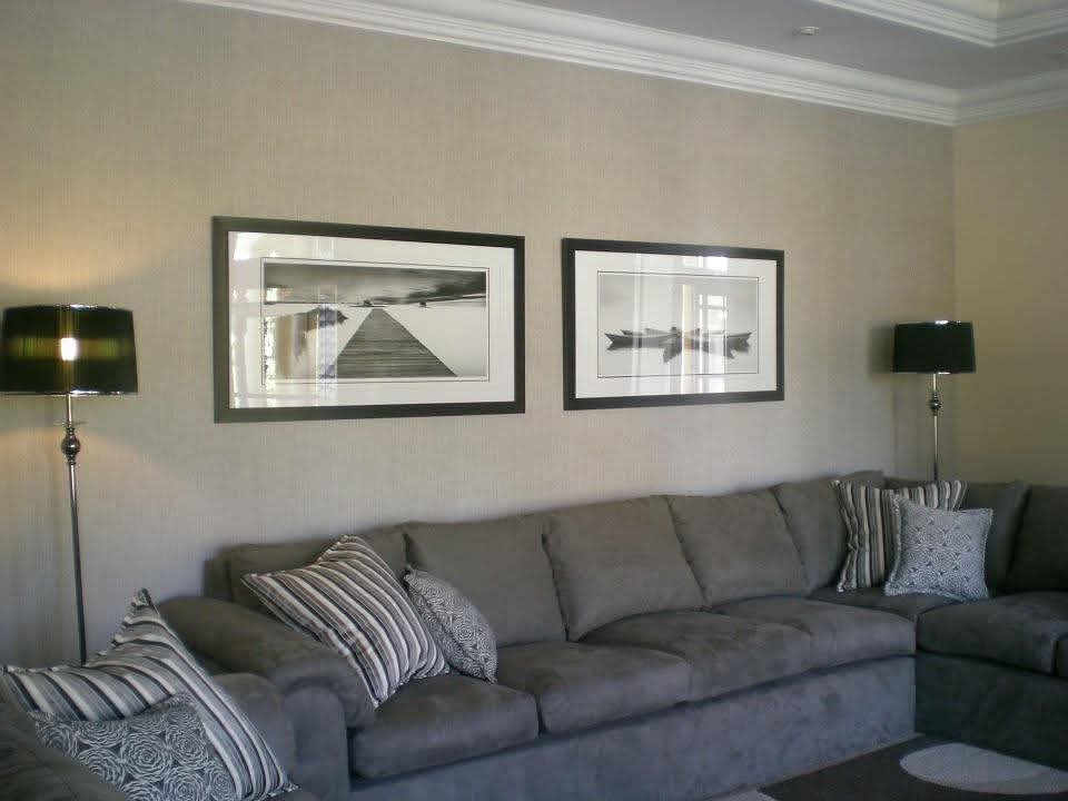 Living space with a gray sectional sofa and framed artwork.