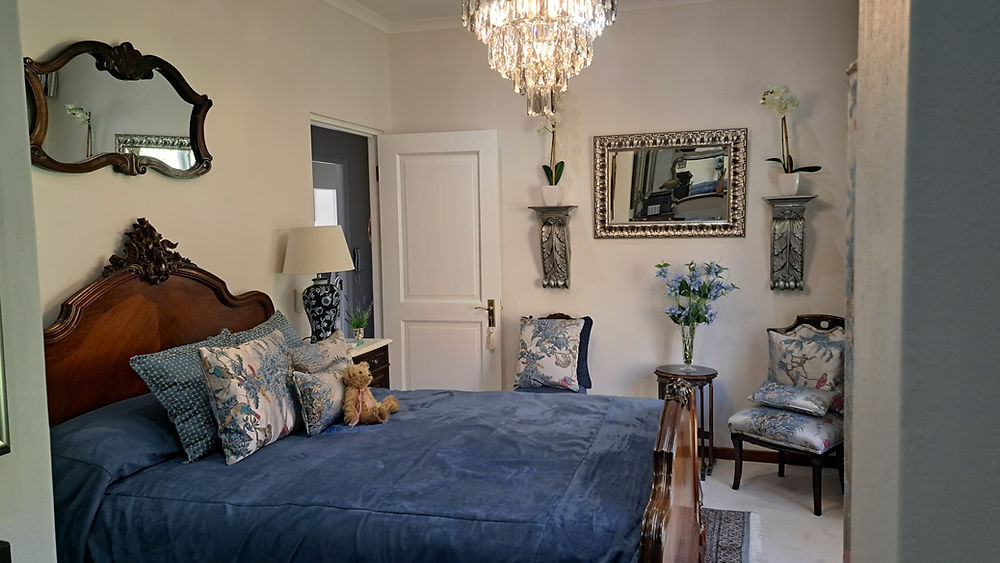 Elegant bedroom space with blue bedding and chandelier.