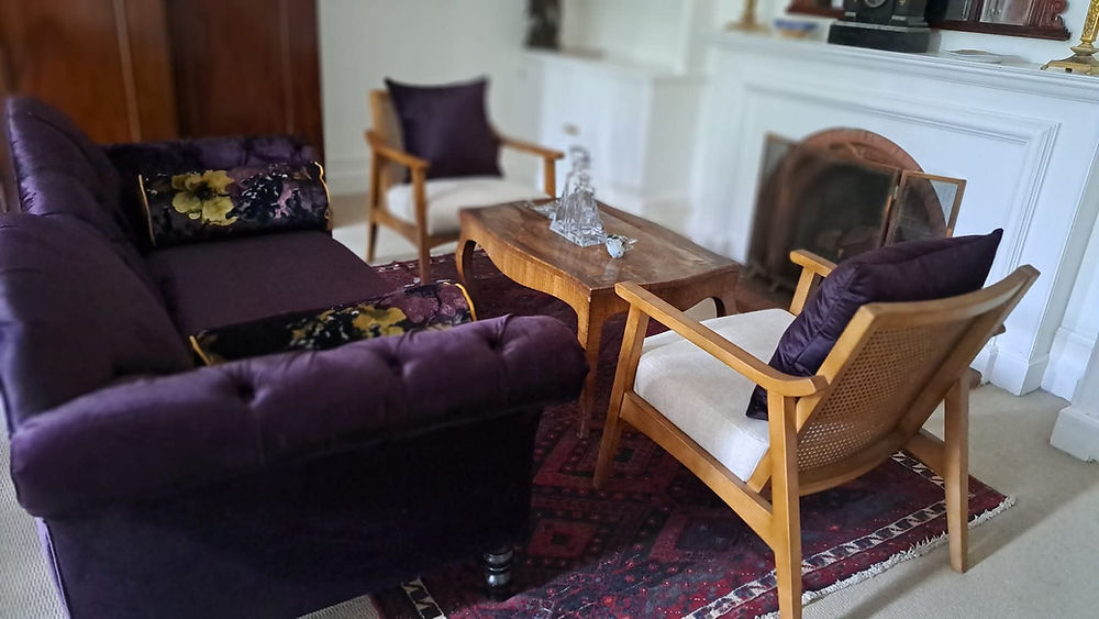 Styled living space with purple sofa, armchairs, coffee table