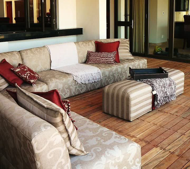 Styled outdoor space with sofa, red pillows, and ottomans