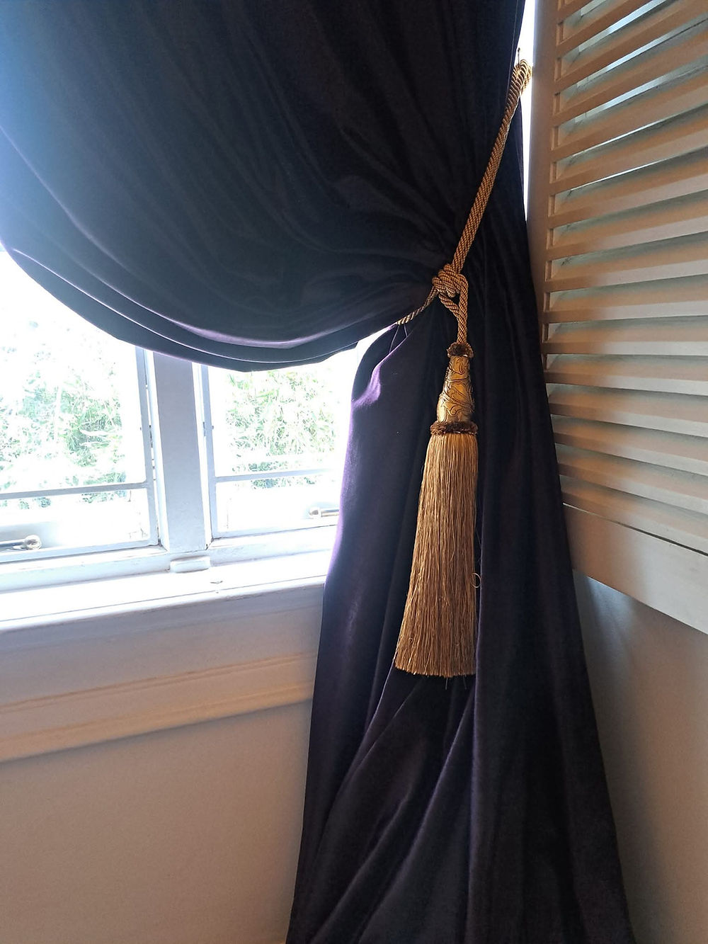 Window with dark curtain tied back, enhancing the space