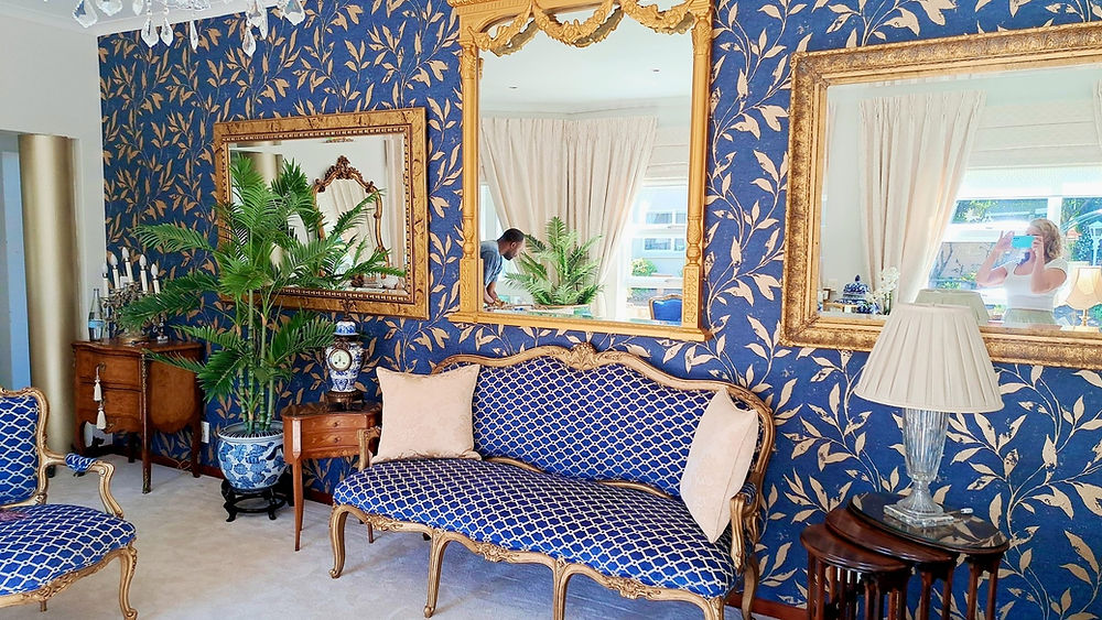 Ornate living space with blue wallpaper and gold mirrors.