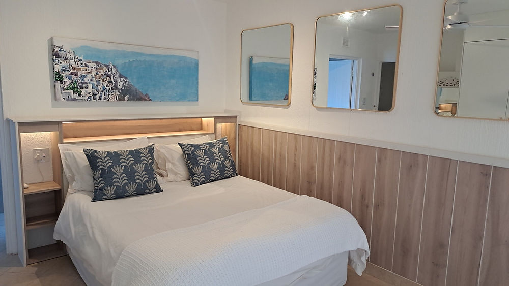Modern bedroom space with queen bed and coastal art