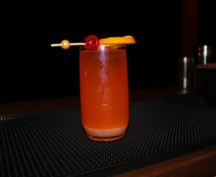 Layered orange and red Sunrise Sip mocktail with cherry and orange garnish, served by Sunshine Sips Mobile Bar.