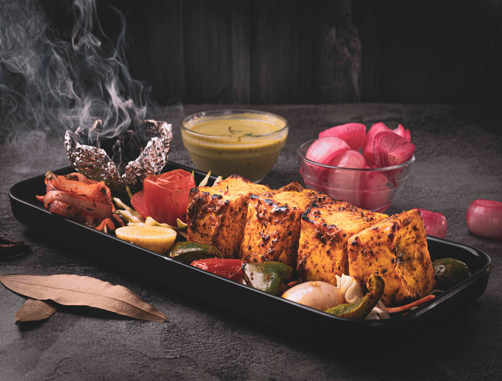 Tandoori paneer platter served on a modern table with a colorful blend of spices and garnishes.