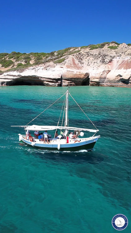 La barca Annina II di Escursione Barca Carloforte Sardegna naviga vicino alla scogliera di Lucchese durante un tour dell'isola di San Pietro